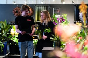 Frivillig fra Jobpatruljen taler med en fritidsjobber i en blomsterbutik