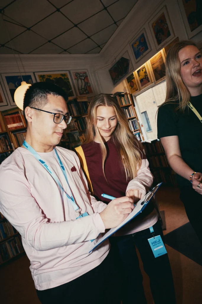 Tre frivillige fra Jobpatruljen besøger en arbejdsplads og taler med medarbejdere, mens de noterer svar på et spørgeskema.